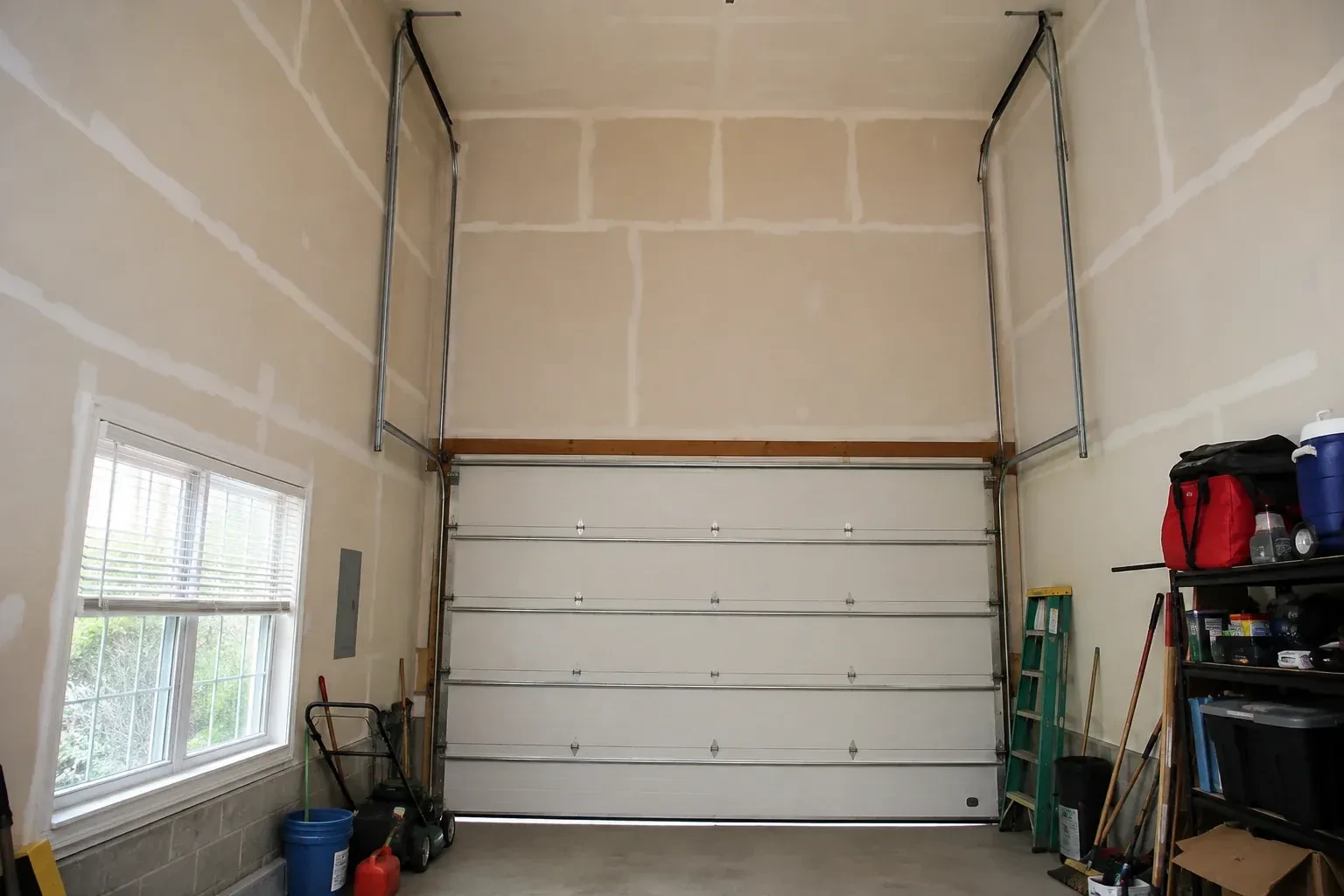 Tall garage interior with a sectional door and tracks extending into overhead space. — High-Lift Garage Door Conversion, Burlington